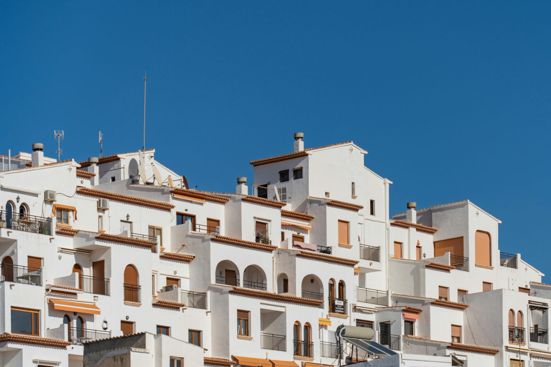 Traditional white Mediterranean buildings against a clear blue sky in Moraira, Spain.
